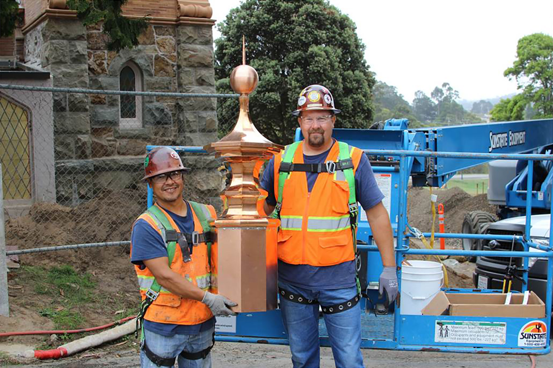 Two workers holding roof finial