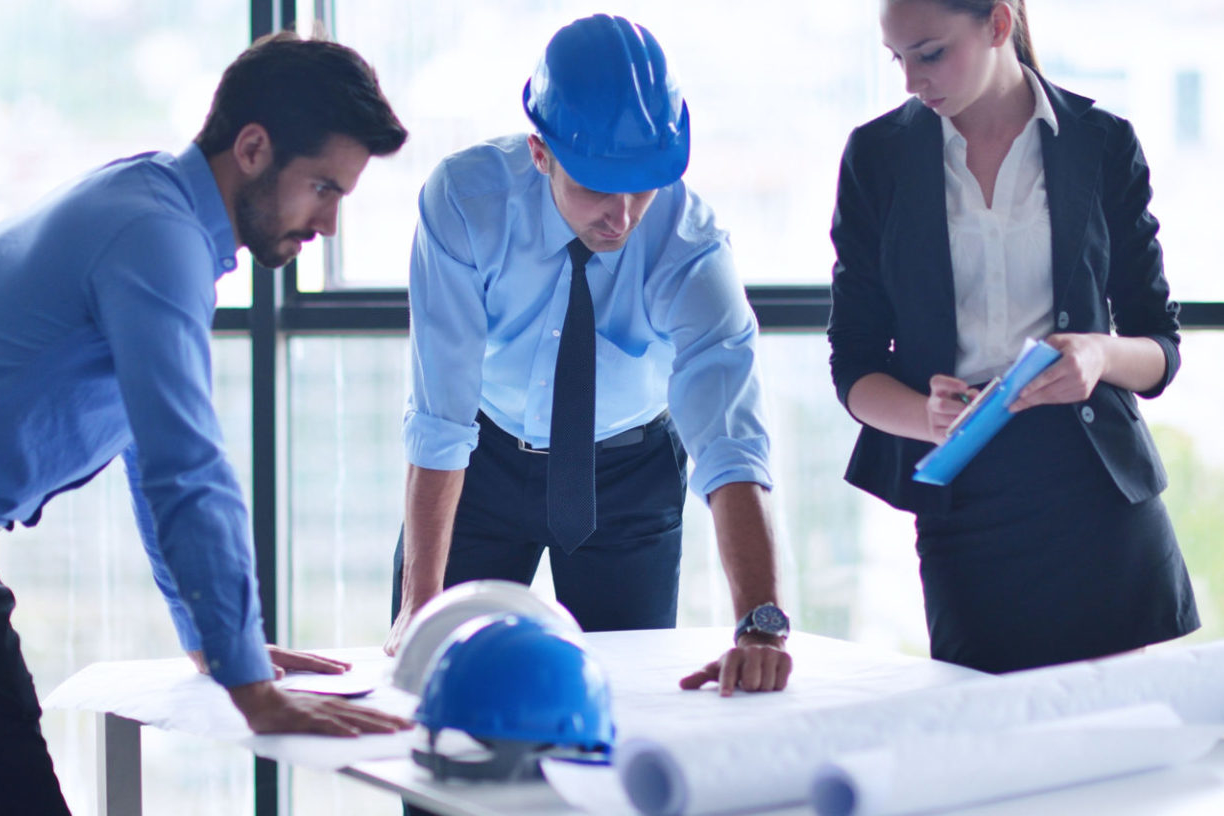 three people in office looking at blueprint