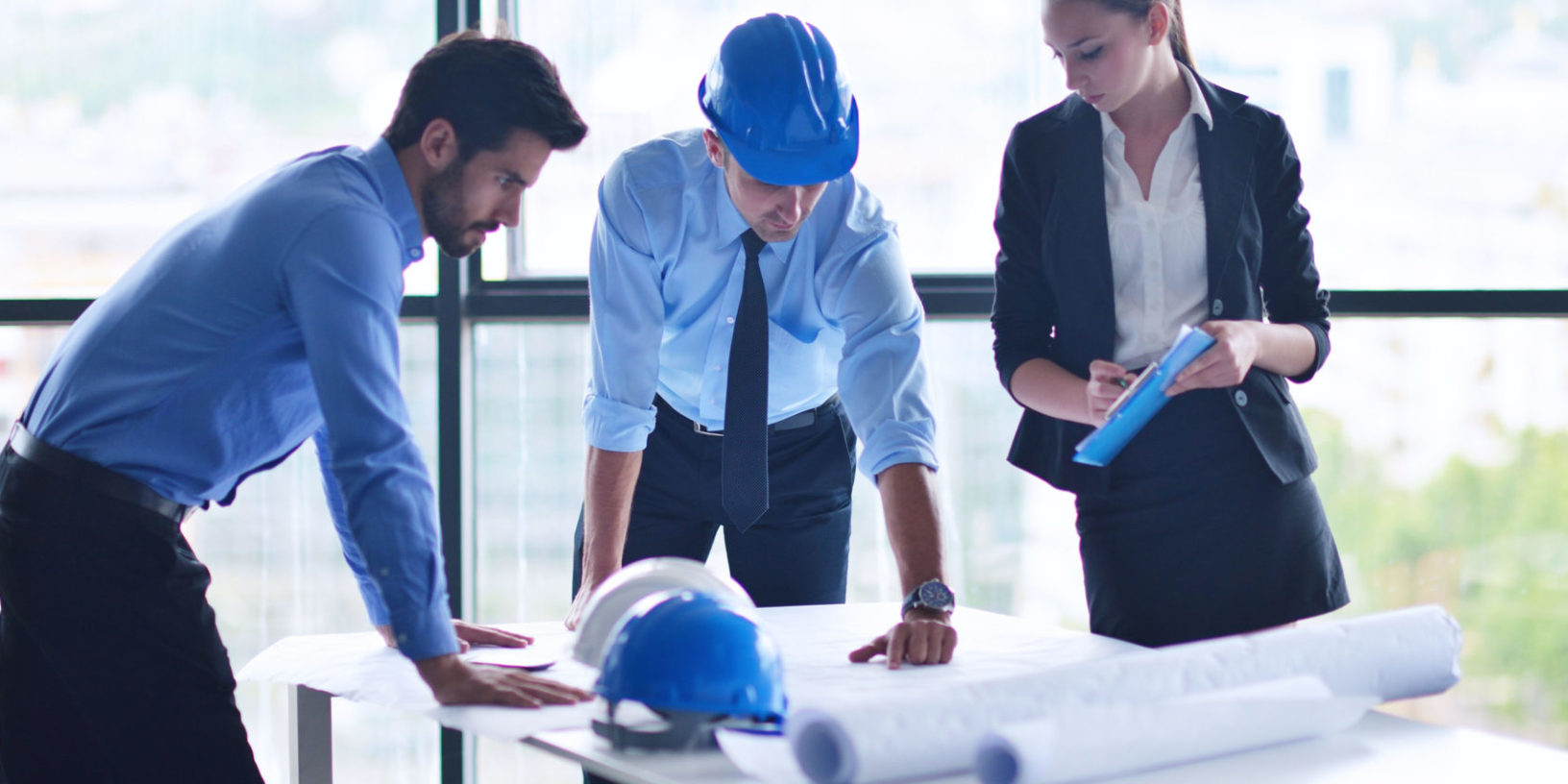 three people in office looking at blueprint