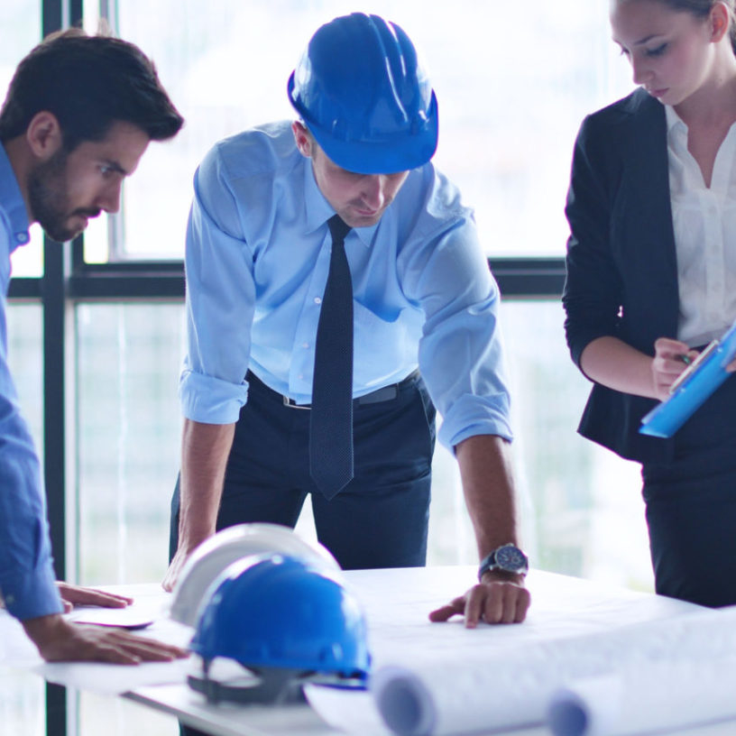 three people in office looking at blueprint