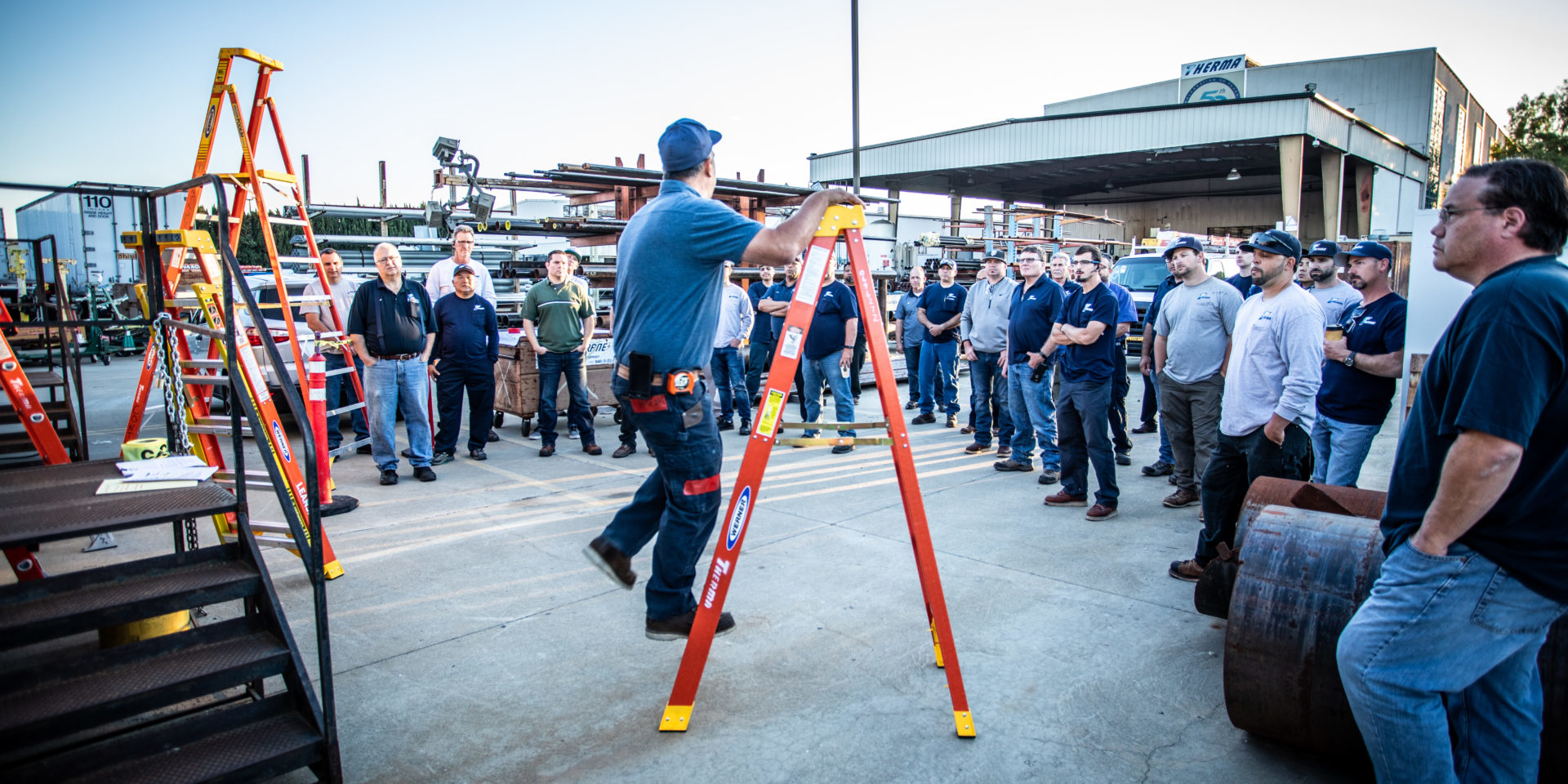 Crowd watching man demonstrate how to use ladders safely